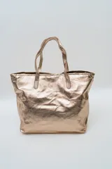 Bolso tipo tote color dorado metalizado, con doble asa de hombro y diseño amplio.