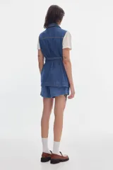 Chaleco midi de denim azul con cierre frontal de botones, cuello camisero, cuatro bolsillos tipo parche y lazo ajustable en la cintura.