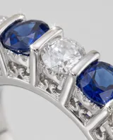 Anillo de plata 925 con diseño de medio sin fin, engastado con cinco piedras de circonia alternadas entre blancas y azul zafiro.
