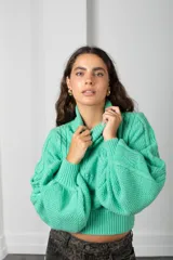 Polera de punto color verde menta, con cuello alto, mangas globo y diseño de trenzas en el frente.