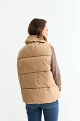 Chaleco puffer de corte holgado y diseño acolchado, con cuello alto y cierre frontal oculto. Presenta cordón ajustable en el ruedo inferior y bolsillos laterales.