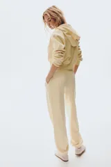 Jogging de felpa color amarillo pálido, con interior cepillado suave. Presenta cintura elástica fruncida con cordón ajustable y elástico revestido en los bajos.