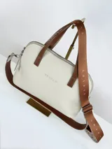 Cartera bandolera de cuero color crema con doble asa de mano marrón y correa larga de cinta con logo.