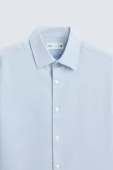 Camisa blanca de manga larga con cuello italiano y cierre frontal de botonadura. Corte regular fit.