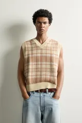 Chaleco relaxed fit de punto tejido en hilatura de algodón, con diseño a cuadros en tonos marrón y beige, cuello en V y acabados en rib en el cuello, las sisas y el ruedo.