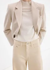 Jeans de corte wide leg en color beige, con tiro medio-alto, bolsillos clásicos y cierre frontal con botón y cremallera.