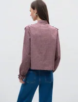 Camisa de manga larga con estampado de cuadros en tonos rojizos, cuello mao y detalle de volados en el frente. Cuenta con cierre frontal de botones y puños con volados.