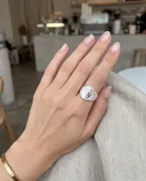 Anillo sello ajustable de acero con placa circular grabada y detalles en relieve en los laterales y la banda.