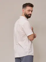 Camisa de manga corta para hombre, color blanco con rayas verticales finas en relieve. Tiene cuello abotonado, bolsillo en el pecho izquierdo y logo bordado pequeño.