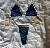 Conjunto de bikini azul con ribetes blancos, compuesto por un corpiño triangular con tiras ajustables y una bombacha colaless con el texto "Brasil" y la bandera bordados en el frente.