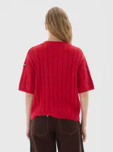 Buzo tejido de manga corta color rojo, con cuello redondo y diseño de punto acanalado y trenzado.