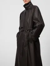 Gabardina larga color marrón con acabado efecto encerado, cuello con solapas anchas, cierre cruzado y bolsillos laterales. Incluye cinturón ajustable y detalles de trabillas en los puños.