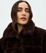 Campera de pelo artificial color marrón oscuro, con diseño de gajos horizontales, manga larga y cuello alto estructurado.