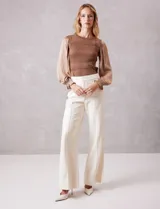 Pantalón de ecocuero color blanco, de corte wide leg, con pretina con cierre y broche interno. Presenta costura frontal en la pierna y bolsillos traseros simulados.