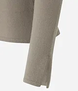 Suéter de punto ajustado en color marrón oscuro, con escote canoa y mangas largas que presentan una pequeña abertura en los puños. Diseño minimalista y versátil con acabado liso.