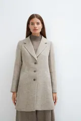 Saco corto entallado de lana fina, con cuello solapa, manga larga y cierre frontal con botones. Presenta un diseño clásico con textura de espiga en tonos tierra.