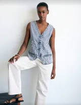 Chaleco de jean celeste con lavado ácido, con botones metálicos y apliques de flores blancas.