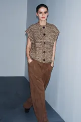 Chaleco de punto grueso con textura jaspeada, cuello redondo, cierre frontal con botones y diseño sin mangas.