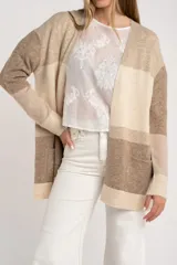 Cardigan abierto de punto con diseño de bloques de color en tonos beige, marrón y bordó. Presenta mangas largas, corte recto y bolsillos frontales aplicados.