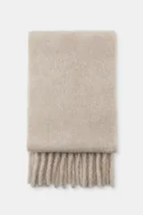 Bufanda de tejido grueso y textura suave en color beige, con diseño liso y terminaciones con flecos a tono en los extremos.