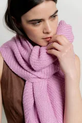 Bufanda de gran tamaño en color rosa, confeccionada en tejido de punto con textura y terminación en flecos en los extremos.