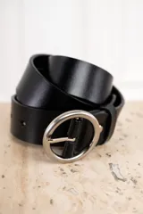 Cinto de cuero negro, ancho, con hebilla metálica plateada de forma ovalada o redonda.