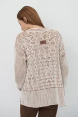 Buzo reversible de tejido de punto con diseño de trenzas, cuello redondo y mangas largas. Presenta una combinación de colores en contraste, con un lado en violeta y el otro en marrón oscuro.