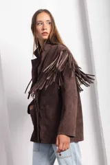 Campera marrón de gamuza con corte masculino, hombros marcados y caída recta. Tiene flecos largos en la espalda y mangas.