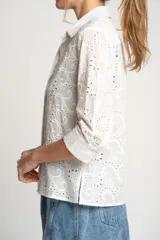 Camisa blanca de algodón con bordado calado tipo broderie, corte recto, cuello camisero y mangas 3/4.