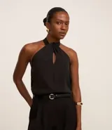 Blusa negra sin mangas confeccionada en chiffon, con cuello halter y abertura en forma de gota en el escote.