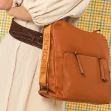 Cartera mochila negra de símil cuero con diseño convertible, bolsillo frontal con cierre y tirador, apertura superior doble y correas ajustables.
