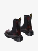 Bota Chelsea color bordó con puntera cuadrada, suela angular y tacón bajo. Presenta inserciones elásticas laterales y el clásico tirador de talón amarillo con el logo de la marca.