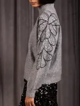 Buzo de cuello alto color gris, de manga larga, con detalle de bordado floral con lentejuelas en el hombro y parte superior de la manga.