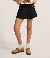 Short pollera negro, confeccionado en bengalina, con hebilla lateral y pliegues.