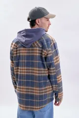 Sobrecamisa a cuadros en tonos azul marino, beige y marrón, con cierre frontal de botones, bolsillos con solapa en el pecho y mangas largas.