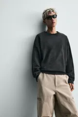 Sudadera de corte relaxed fit confeccionada en tejido de algodón con interior de rizo. Presenta cuello redondo, manga larga y acabados en rib, con un acabado de efecto lavado que le otorga una apariencia única.