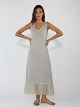 Vestido midi de punto metalizado en color plateado, sin mangas, con escote en V y detalle de flecos en el ruedo.