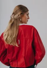 Campera bomber de cuero color marrón, con mangas abullonadas, puños elásticos y cierre frontal con botones a presión.