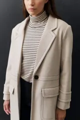 Rompeviento color beige con rayas horizontales finas en marrón, cuello alto y mangas largas.