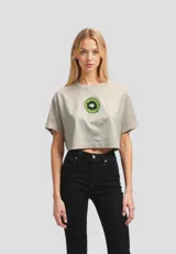 Remera cropped de algodón color beige claro, con cuello redondo y manga corta doblada. Presenta un estampado frontal de un kiwi cortado a la mitad.