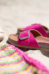 Sandalia de cuero color fucsia, con plantilla anatómica marrón y hebilla dorada ajustable.