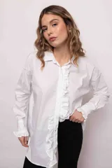 Camisa blanca de algodón con cuello clásico, cierre frontal con botones, mangas largas con puños abotonados y volados en el frente y los puños.