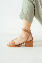 Sandalias de cuero color suela con taco cuadrado bajo y tira ajustable con hebilla en el tobillo.