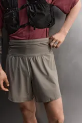 Short deportivo de trail running confeccionado en tejido técnico elástico con textura. Presenta una cintura elástica ancha con compartimentos integrados, bolsillo trasero con cierre y aberturas laterales en el bajo.