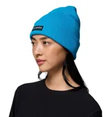 Gorro tipo beanie de punto acanalado en color azul brillante, con diseño de puño enrollado y parche rectangular con el logo de Columbia en el frente.