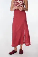 Falda larga color rojo ladrillo, de corte recto y tiro alto, con abertura lateral pronunciada.