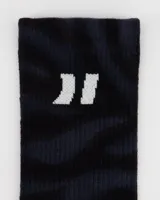 Par de medias deportivas de caña media, color negro con patrón de rayas oscuras (efecto cebra o tigre). Presentan el texto "ART." en blanco en la planta del pie y un logo de comillas dobles en blanco en la parte superior de la caña.