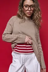 Sweater de tejido de punto negro con tramas de ochos en las mangas y laterales, cuello redondo a la base y mangas largas.