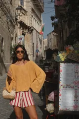 Buzo de punto color beige claro, con tejido acanalado y escote en V. Presenta mangas amplias y corte holgado.