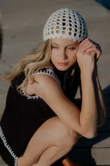 Conjunto de dos piezas tejido en algodón, compuesto por un chaleco sin mangas con cierre frontal de botones y un short de tiro medio. Ambas prendas presentan un diseño en color blanco con detalles de terminaciones en color beige.